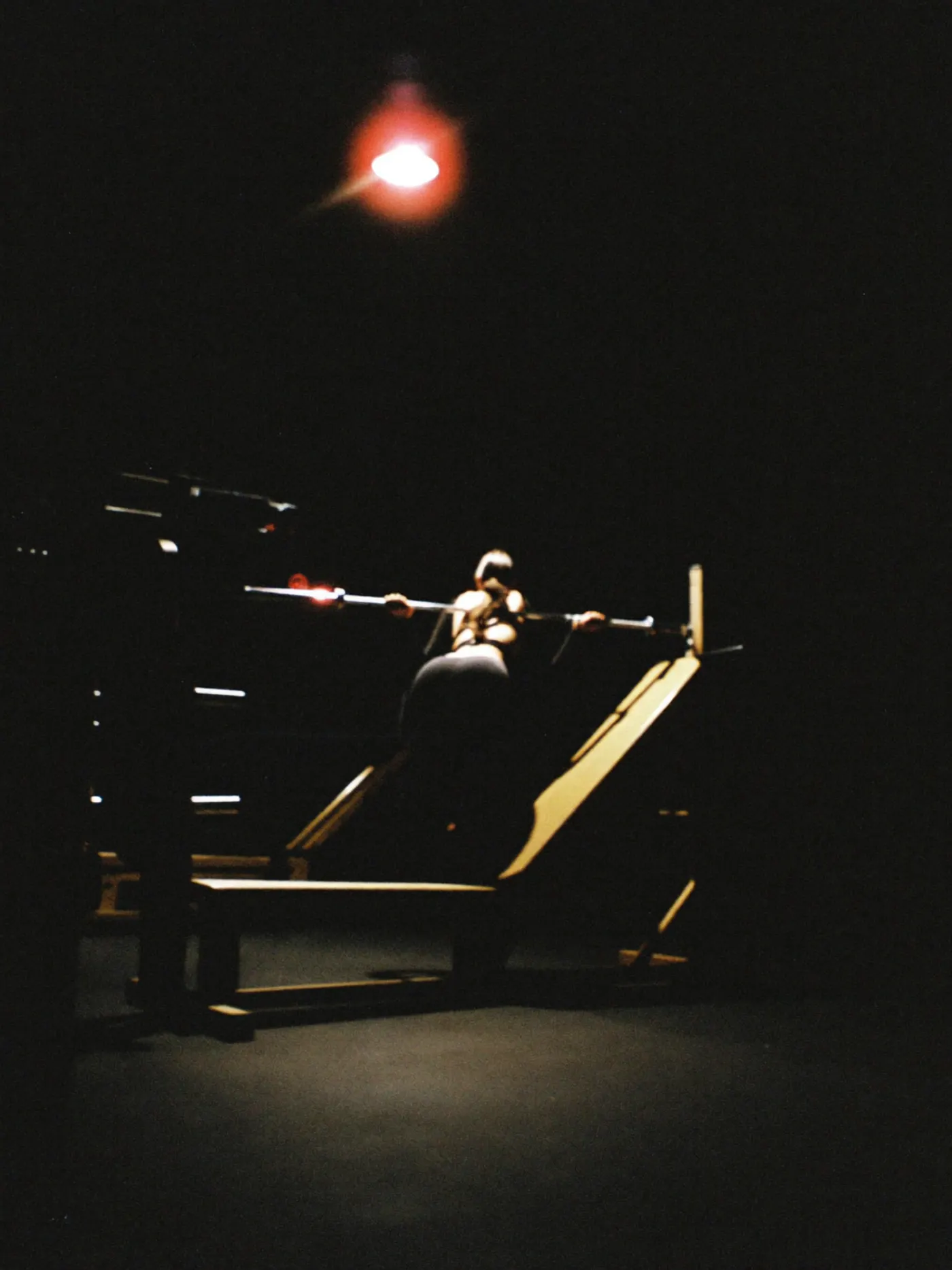 A member training alone on the gym floor late at night, lit by a single overhead light